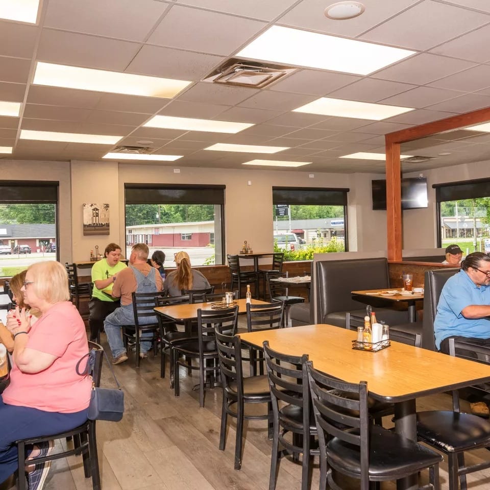 Diners seated at tables and booths in a brightly lit restaurant with large windows.
