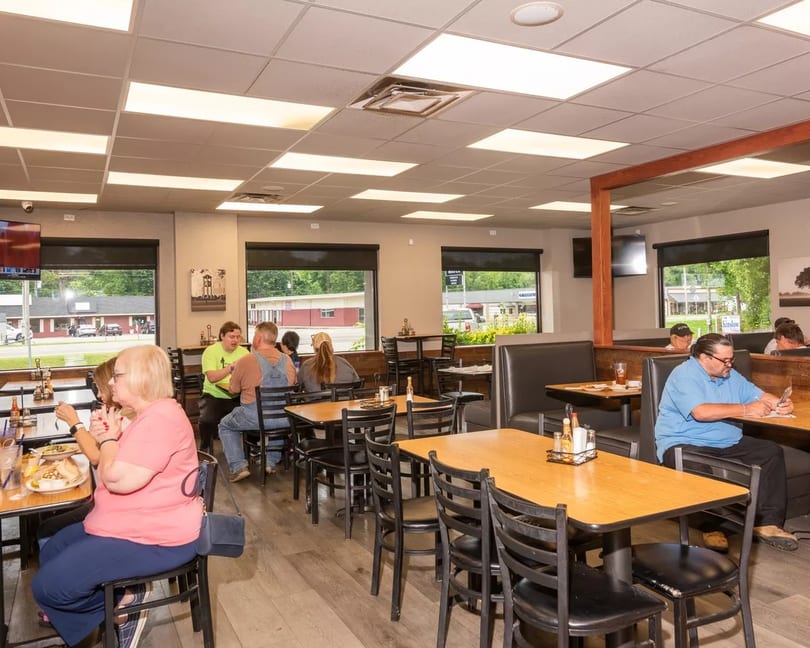 Diners seated at tables and booths in a brightly lit restaurant with large windows.