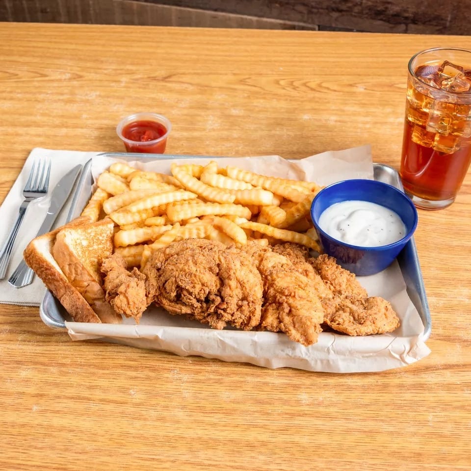 Fried chicken tenders, crinkle-cut fries, Texas toast, and dipping sauces on a tray with iced tea.