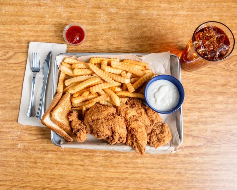 Fried chicken tenders, crinkle-cut fries, Texas toast, dipping sauces, and iced tea on a tray.
